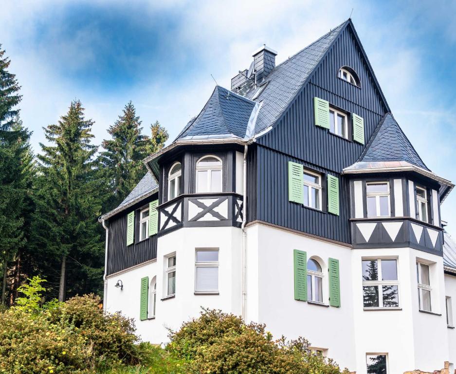 uma grande casa branca com um telhado preto em Ahornallee em Kurort Bärenburg
