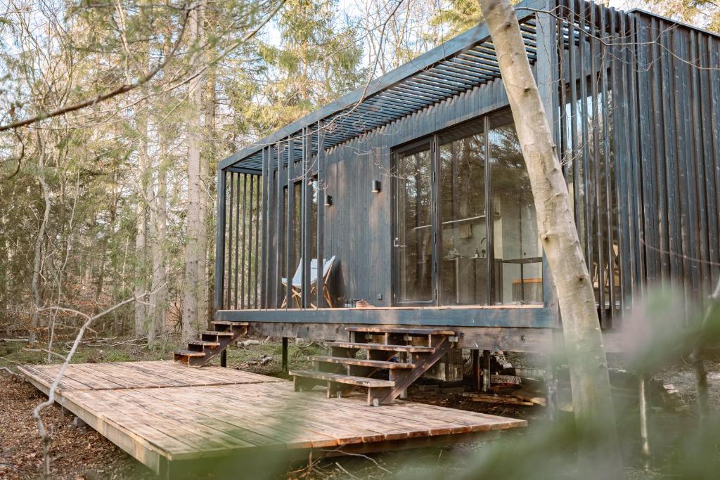 a black house sitting on a wooden platform in the woods at WoodHouse Denmark in Hadsund