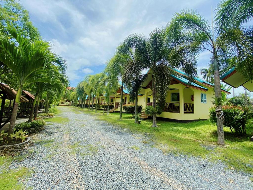 a road lined with palm trees next to a house at Baanrimklong bungalow in Ko Chang