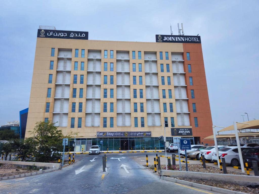 un edificio de hotel con coches aparcados en un aparcamiento en JOIN INN HOTEL Jebel Ali, Dubai - Formerly easyHotel Jebel Ali, en Dubái