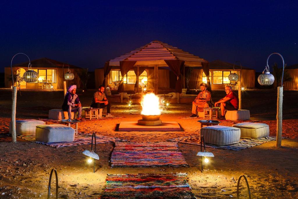 a group of people sitting around a fire at night at Celia Desert Camp in Merzouga