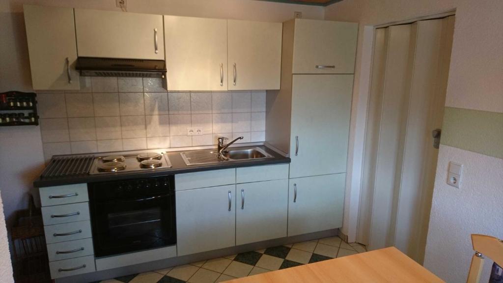 a kitchen with white cabinets and a sink and a stove at Ferienwohnung Käfer in Rust