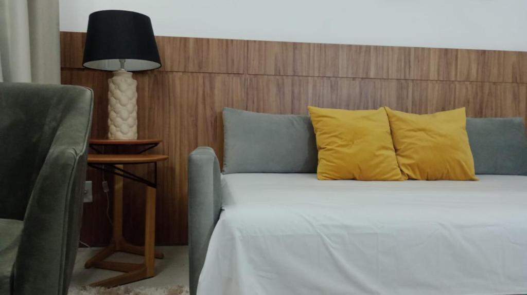 a bedroom with a bed with yellow pillows and a lamp at INOVA FLAT conforto no Condominio Cosmopolitan in Palmas