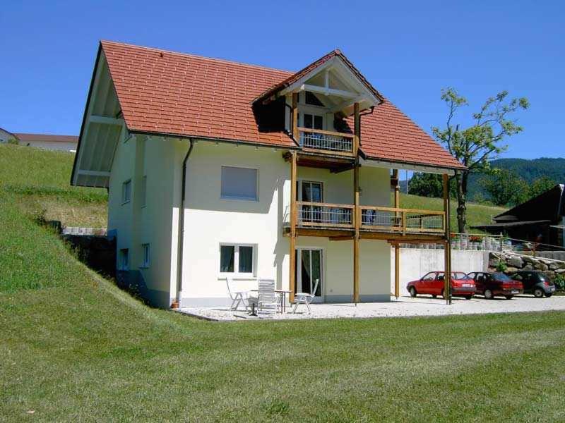 ein großes Haus mit rotem Dach und einem Parkplatz in der Unterkunft Ferienwohnungen Hansmartihof in Horben