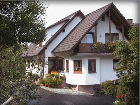 a white house with a roof with flowers on it at Gästehaus Birgitte in Ettenheim