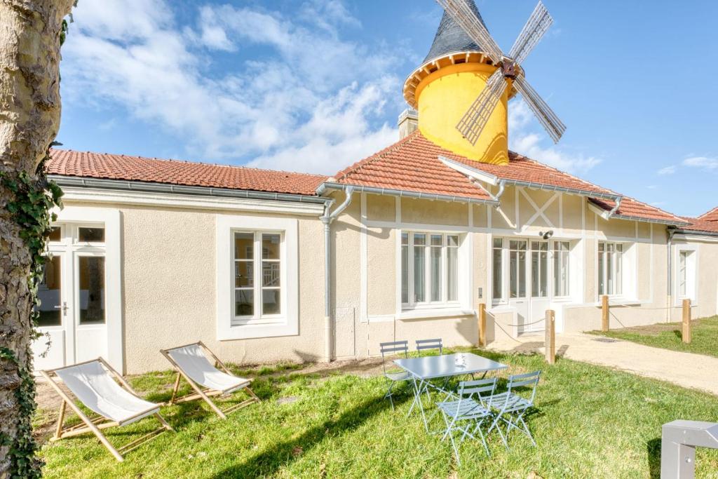 una casa con un molino de viento en el patio en Appartement Aigrette - La Maison Heureuse - Welkeys, en Saint-Georges-dʼOléron
