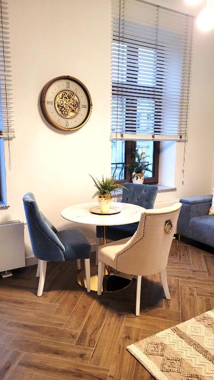 a table and chairs in a living room with a clock at APARTAMENT JARACZA 28/9 in Słupsk