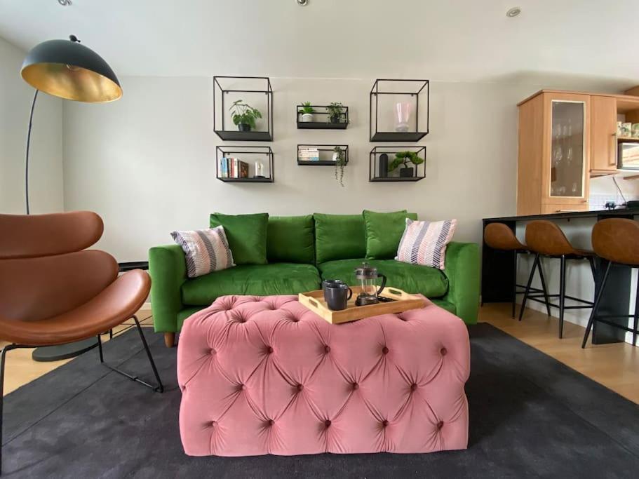 a living room with a green couch and a pink ottoman at 2 Bed House in Hampton - Free parking in Hanworth