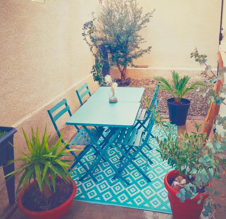 uma mesa azul e cadeiras num pátio com plantas em Narbonne Studio Lamarobile avec jardin et terrasse proche des Grands Buffets, du centre ville et de la gare em Narbona