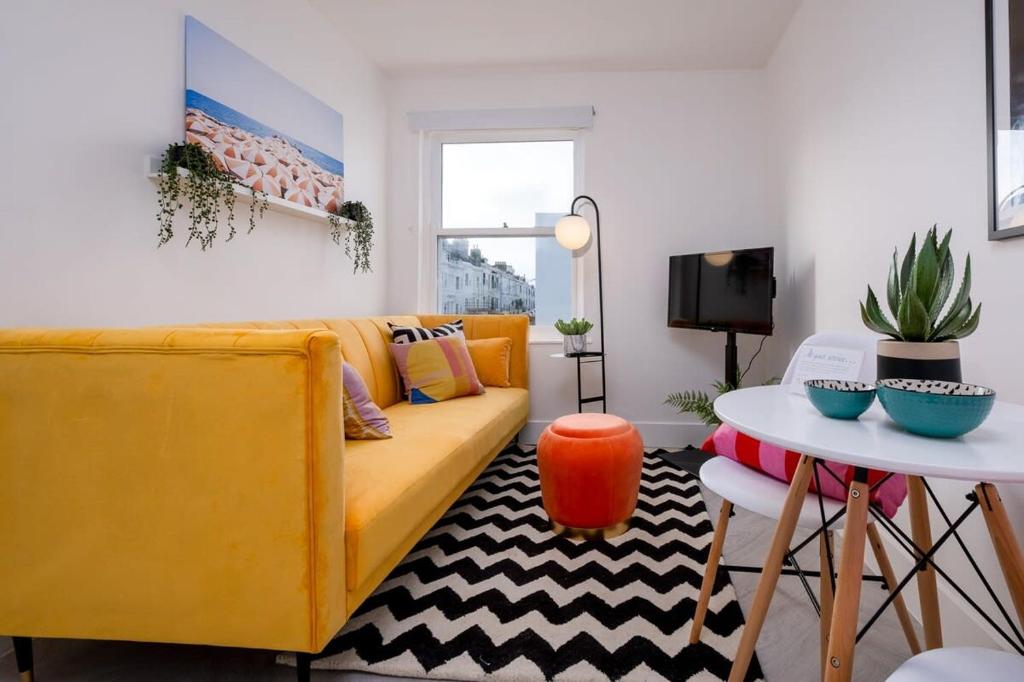 ein Wohnzimmer mit einem gelben Sofa und einem Tisch in der Unterkunft Bright bold beautiful Close to Brighton station in Brighton & Hove