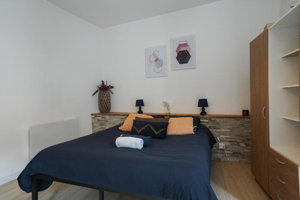 una camera da letto con un letto con lenzuola e cuscini blu di Studio moderne, hypercentre de Cholet, arrivée autonome ! a Cholet