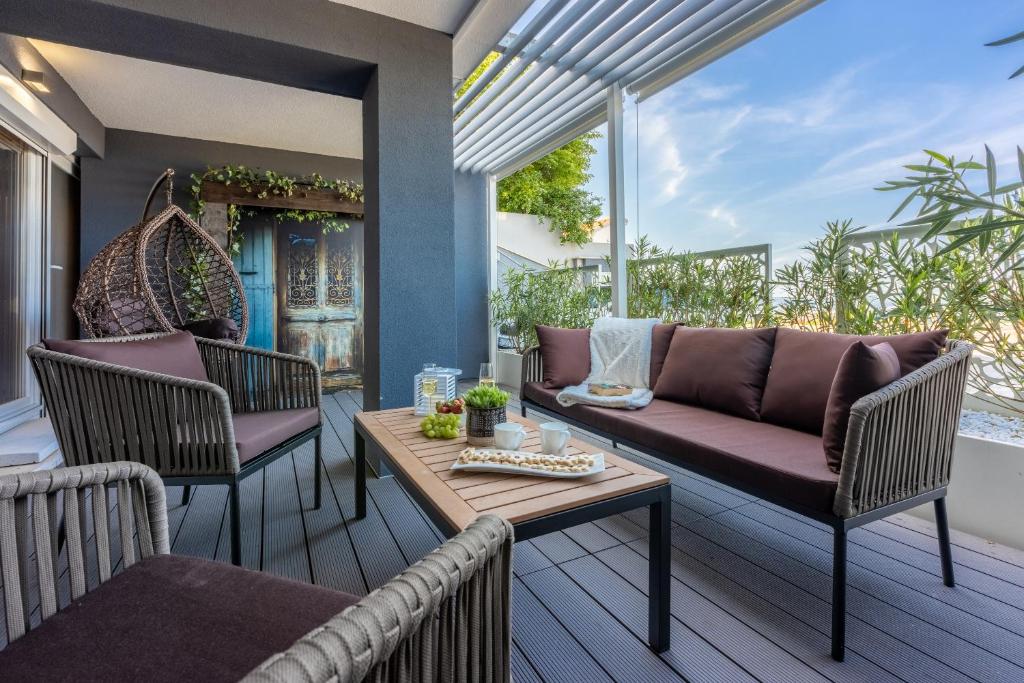 eine Terrasse mit einem Sofa, Stühlen und einem Tisch in der Unterkunft Panoramica Apartment with Whirlpool in Crikvenica