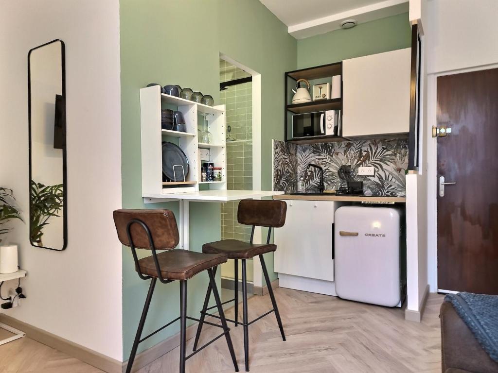 - une cuisine avec 2 chaises et un réfrigérateur blanc dans l'établissement Le Pastelier - Parking privé - Clim, à Albi