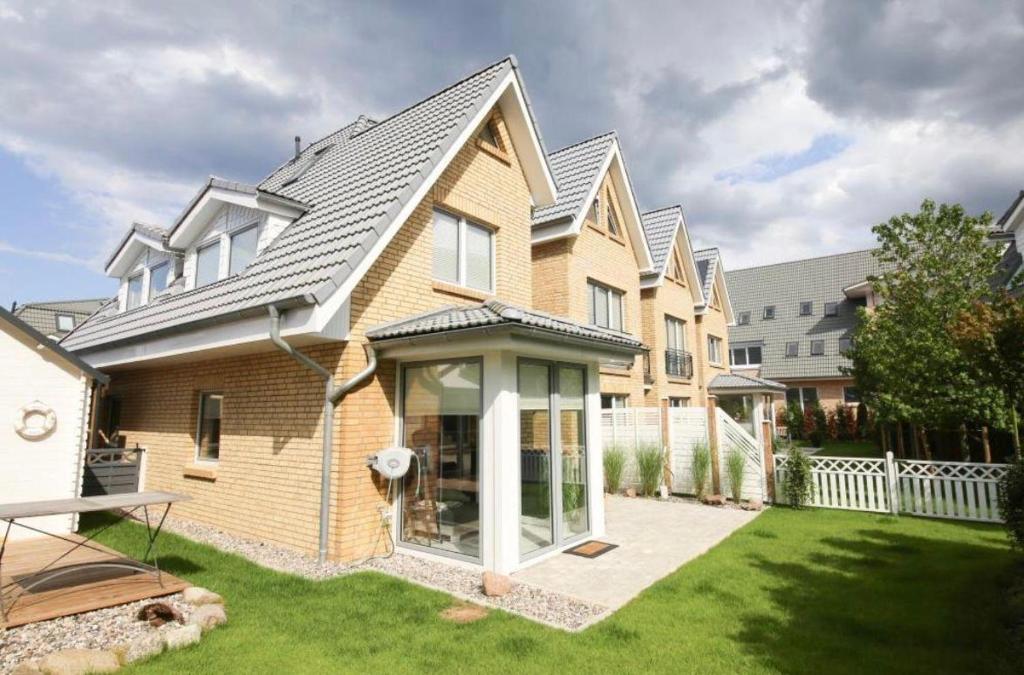 uma casa com um telhado inclinado e um quintal em Sealect-Hus-4-Timmendorfer-Strand-mit-Sauna em Timmendorfer Strand