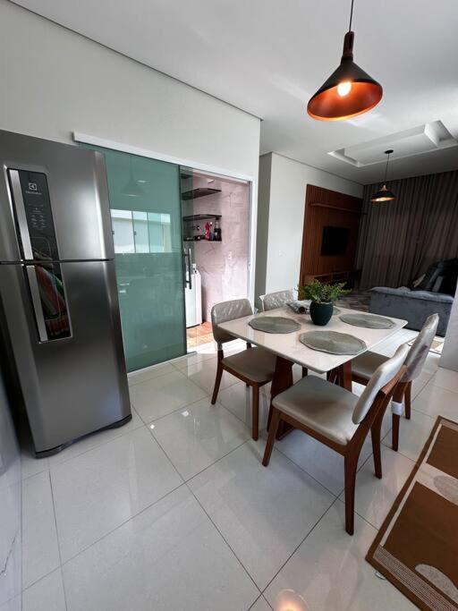 a kitchen with a table and a stainless steel refrigerator at Casa Impecável in Palmas