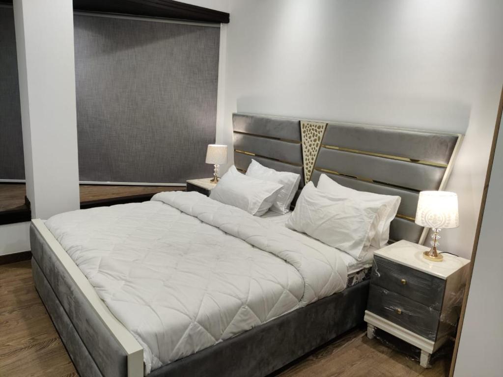 a bedroom with a large bed with a silver headboard at Premium&Cozy Two Beds DHA in Lahore