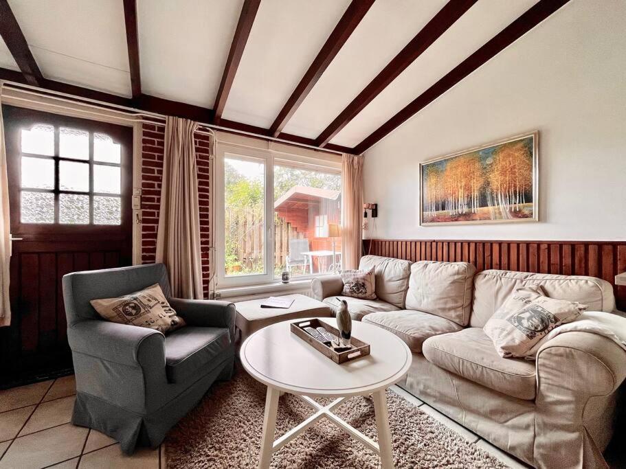 een woonkamer met een bank, stoelen en een tafel bij Garnekuul 53 in Callantsoog