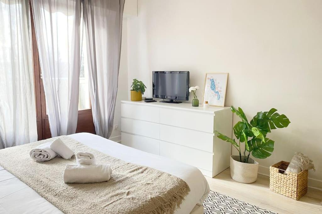 a white bedroom with a bed and a tv at Le Syrme • 450m de la plage, balcon & parking in Annecy