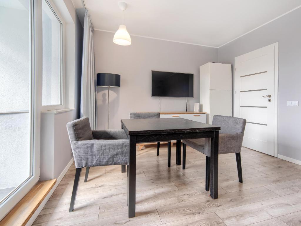 a dining room with a black table and chairs at Platinium Zaspa - Pilotów 14 in Gdańsk