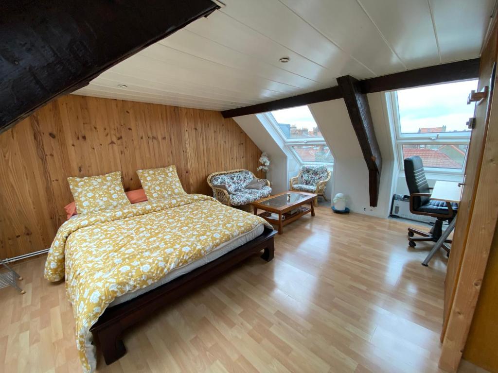 um quarto com uma cama, uma secretária e uma cadeira. em Maison malouine proche de plage em Dunkerque