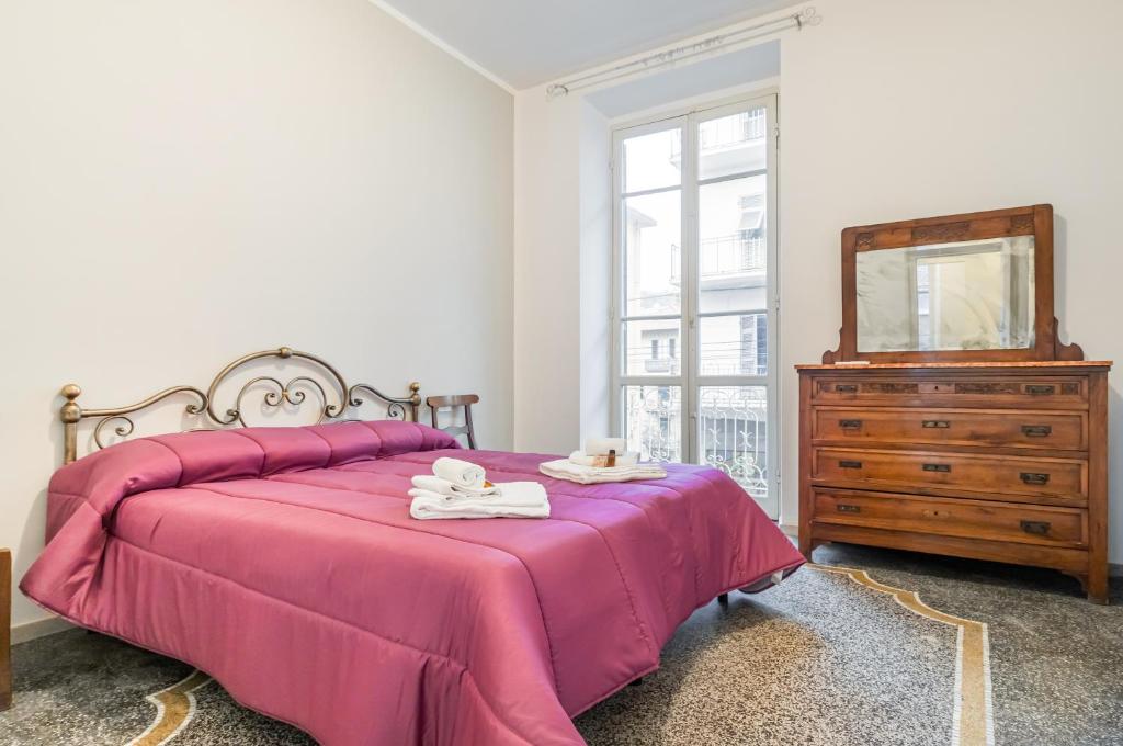 1 dormitorio con cama rosa, tocador y espejo en Casa Shakespeare, en La Spezia