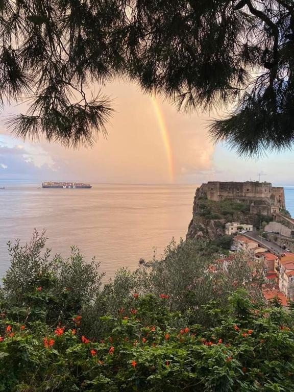 a rainbow in the sky over the ocean with a city at Casa Santacroce in Scilla