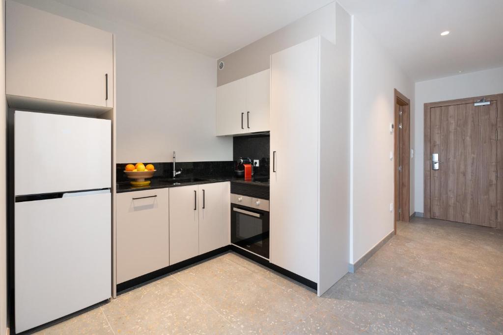 a kitchen with white cabinets and black counter tops at ASA Hotel La Marina in Ondara