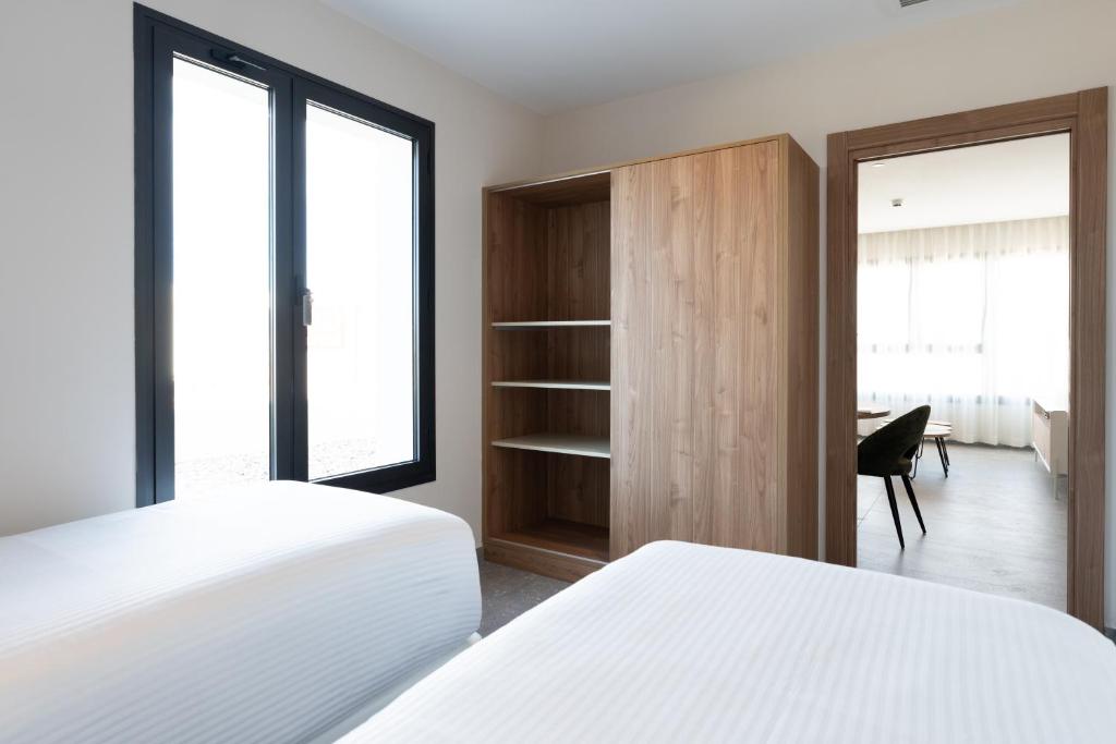 a bedroom with two beds and a closet and a desk at ASA Hotel La Marina in Ondara