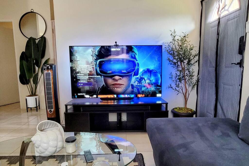 uma sala de estar com uma televisão grande com um auscultador de realidade virtual em Gated Cozy Urban Luxe Retreat em Portmore