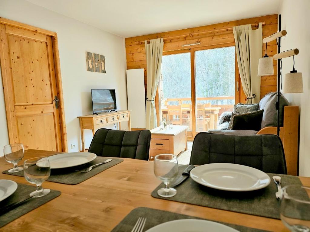 ein Esszimmer mit einem Tisch mit Tellern und Weingläsern in der Unterkunft La rivière d'argent T3 Serre Chevalier Pied des pistes in Saint-Chaffrey