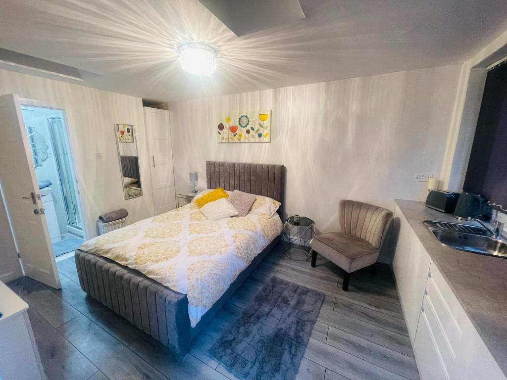 1 dormitorio con cama, silla y lavamanos en Private guest house/Annexe, en Mánchester