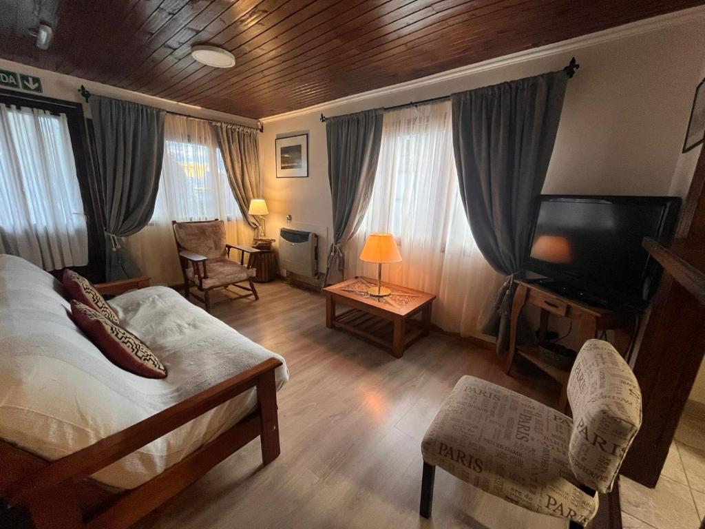 Schlafzimmer mit einem Bett und einem Flachbild-TV in der Unterkunft Cálida Cabaña en el Corazón de Ushuaia in Ushuaia
