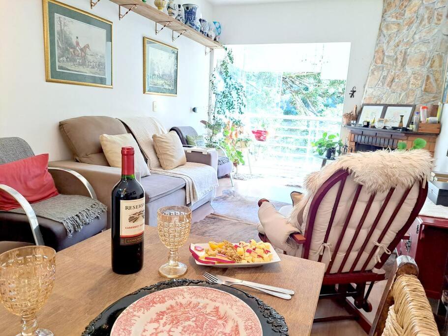 een woonkamer met een tafel met een fles wijn bij Apto Varanda Verde com Lareira in Campos do Jordão
