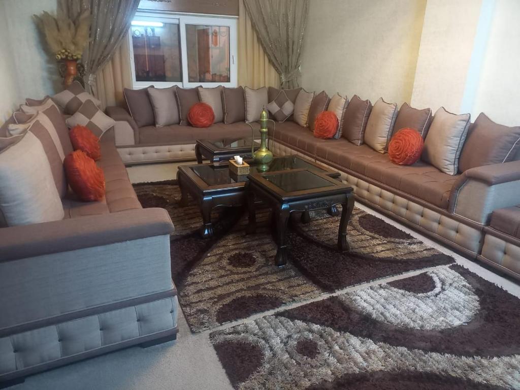 un soggiorno con un grande divano e tavoli di شقه مفروشه مع حديقه اربد بجانب مدارس دار العلوم a Irbid