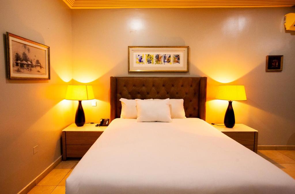 a bedroom with a large bed with two lamps at Genesis Reventon Hotel in Port Harcourt