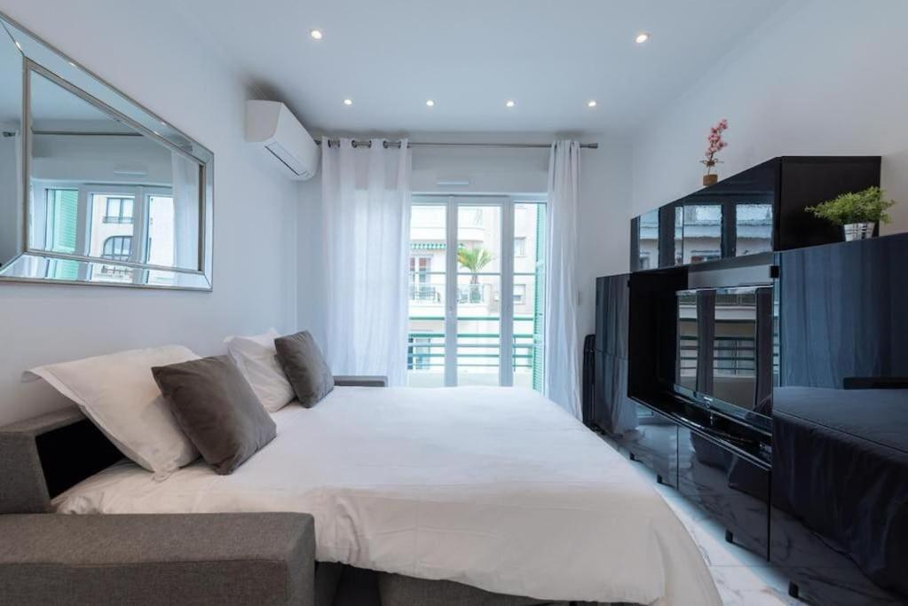 um quarto branco com uma cama e uma televisão em CENTER JUAN LES PINS 50 M DES PLAGES em Antibes