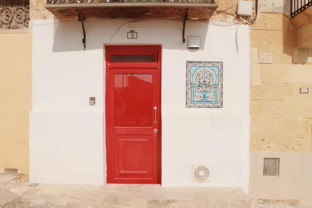 una puerta roja en el lateral de un edificio en Studio Barrakka Gardens, en La Valeta