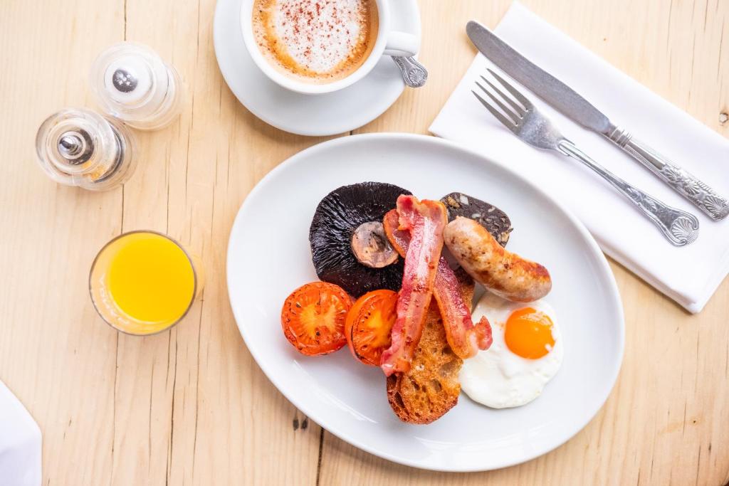 a plate of breakfast food with eggs bacon and tomatoes at Crown Hotel in Southwold