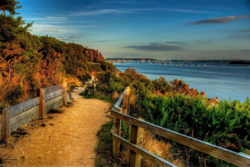 a path next to a fence next to the water at Lovely 2 Bed 2 Bath Flat with FREE Parking in Poole