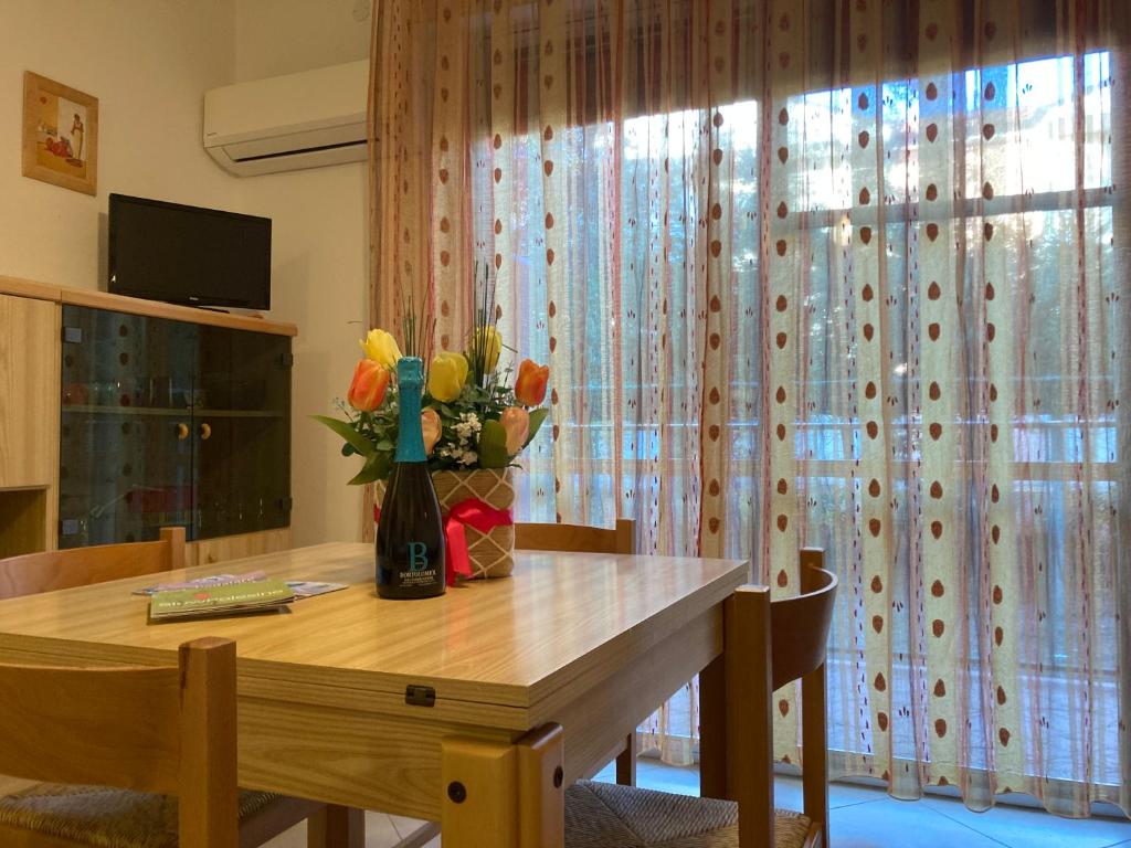 a dining room table with a vase of flowers on it at Giovanna in Rosolina Mare