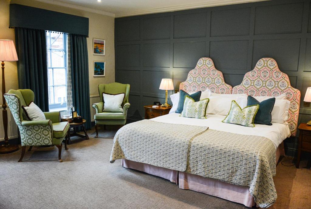 a bedroom with a large bed and two chairs at Crown Hotel in Southwold