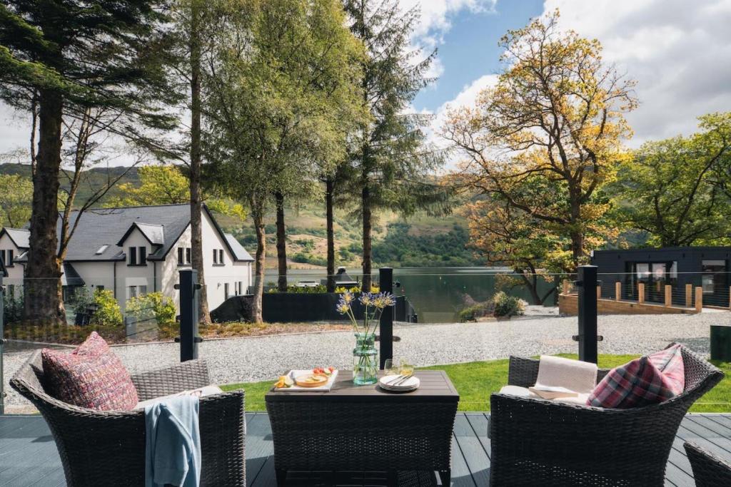 a patio with a table and chairs with a view of a house at Ardlui Retreat Lodge 1 in Arrochar