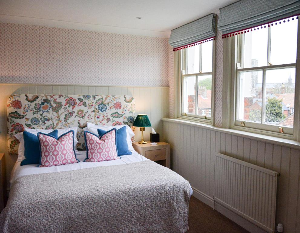 a bedroom with a bed with blue and pink pillows at Crown Hotel in Southwold
