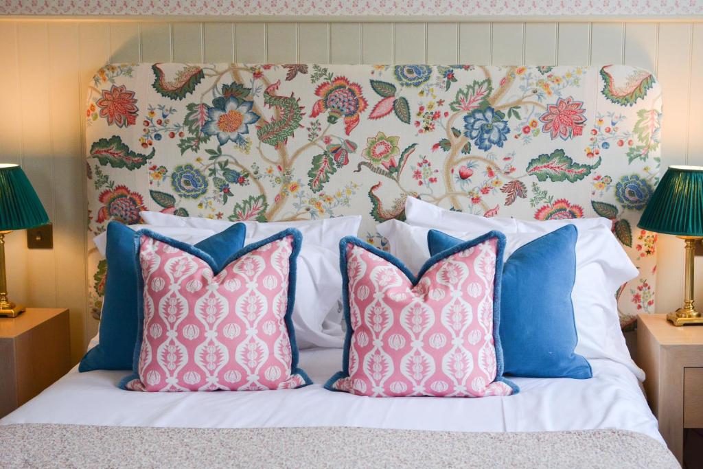 a bed with four pillows and a floral headboard at Crown Hotel in Southwold