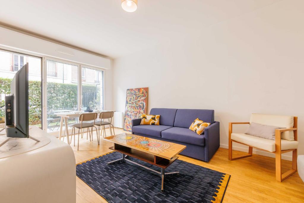 ein Wohnzimmer mit einem blauen Sofa und einem Tisch in der Unterkunft Cosy Apartment 4P 1BDR Clichy proche Paris in Clichy