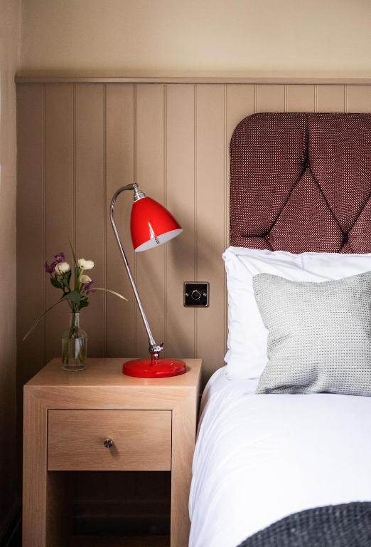 a red lamp on a night stand next to a bed at Crown Hotel in Southwold