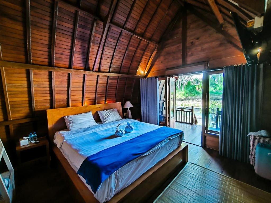 Cette chambre en bois comprend un grand lit. dans l'établissement Eling Ubud Guesthouse, à Ubud