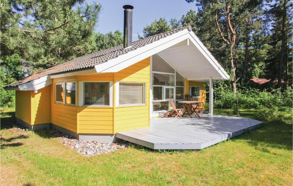 a small yellow cottage with a deck in a yard at 2 Bedroom Amazing Home In Hjby in Lumsås