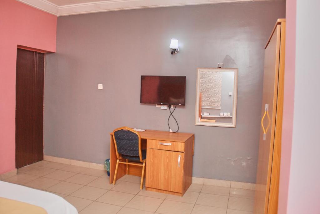 um quarto com uma secretária e uma televisão na parede em GLAMOUR PARK'S HOTEL, ABUJA em Abuja
