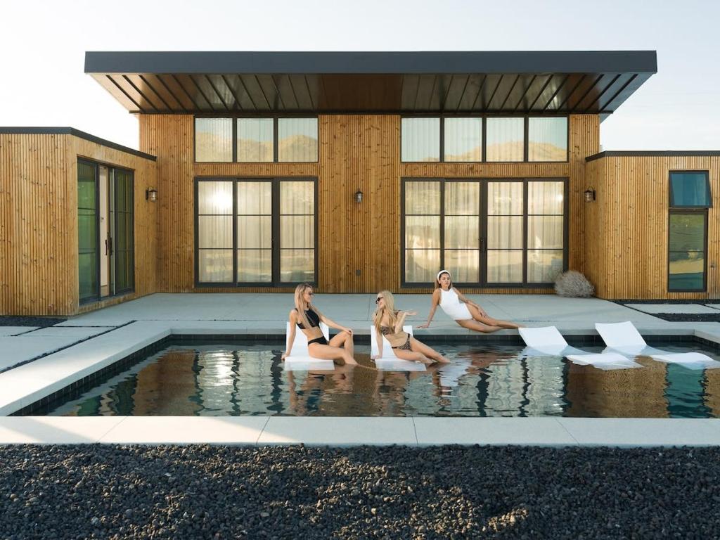 drei Frauen sitzen im Wasser in einem Pool in der Unterkunft The Lunawood - Lux Home Pool and Spa in Joshua Tree